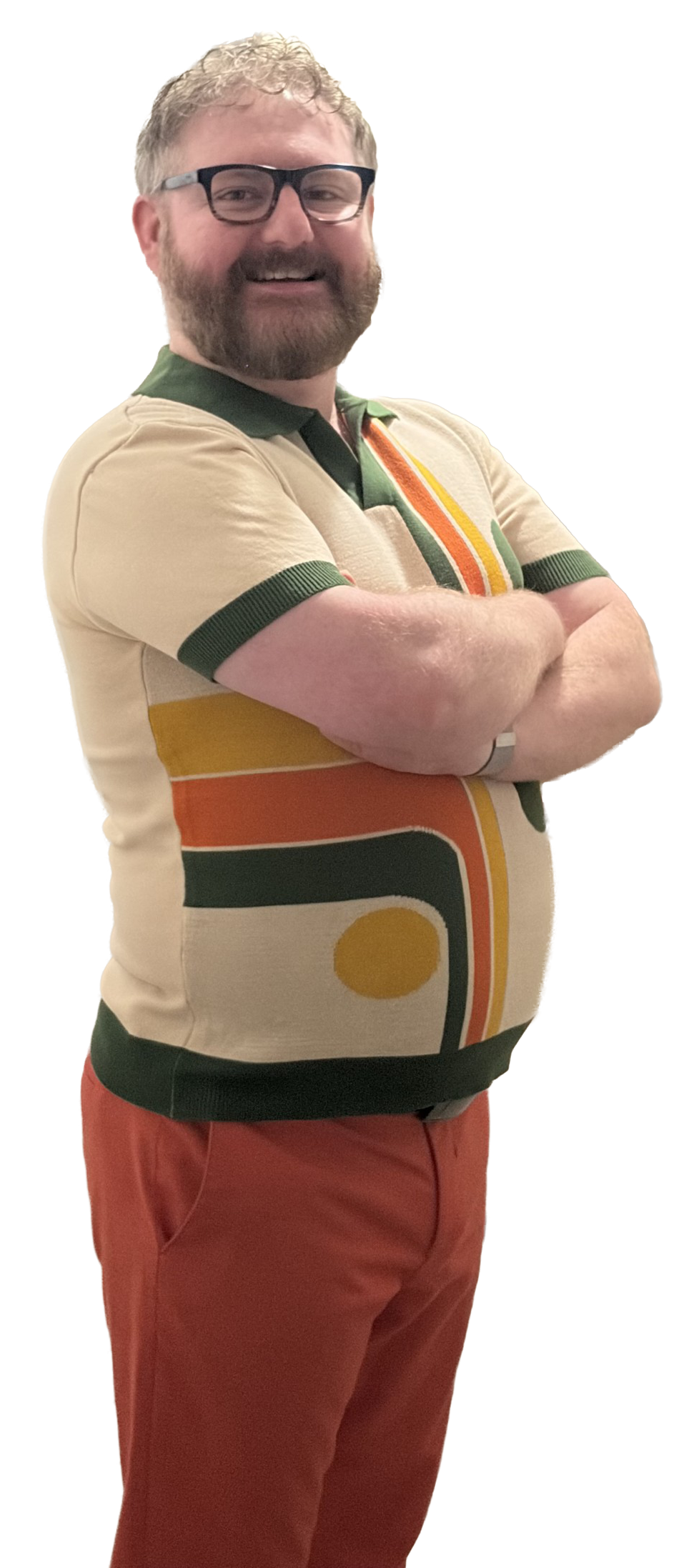 A smiling person with glasses, arms crossed, wearing a retro-style shirt and red pants